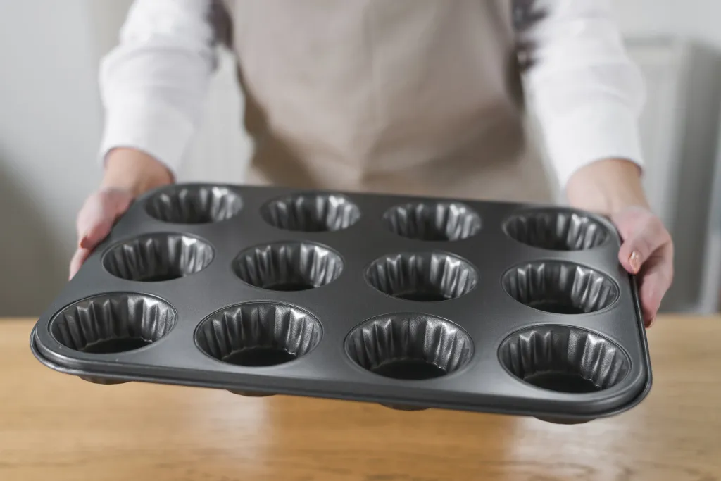 close-up-woman-s-hand-holding-metal-muffin-cupcake-tray-pan.jpg антипригарная форма для кексов